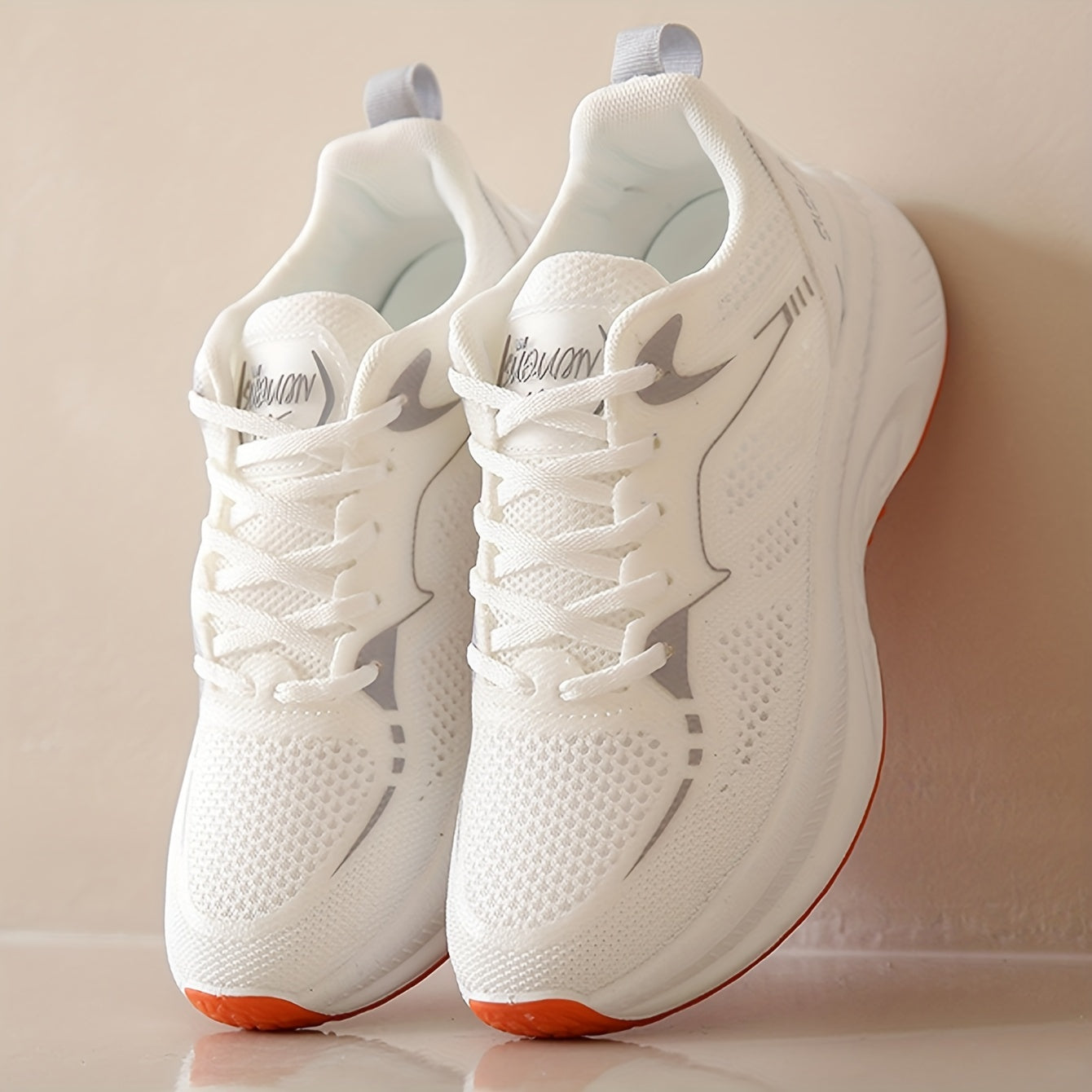 Women's low-top running shoes in white with orange sole, breathable fabric upper, rubber sole, stabilizing support, all-season casual sneakers.