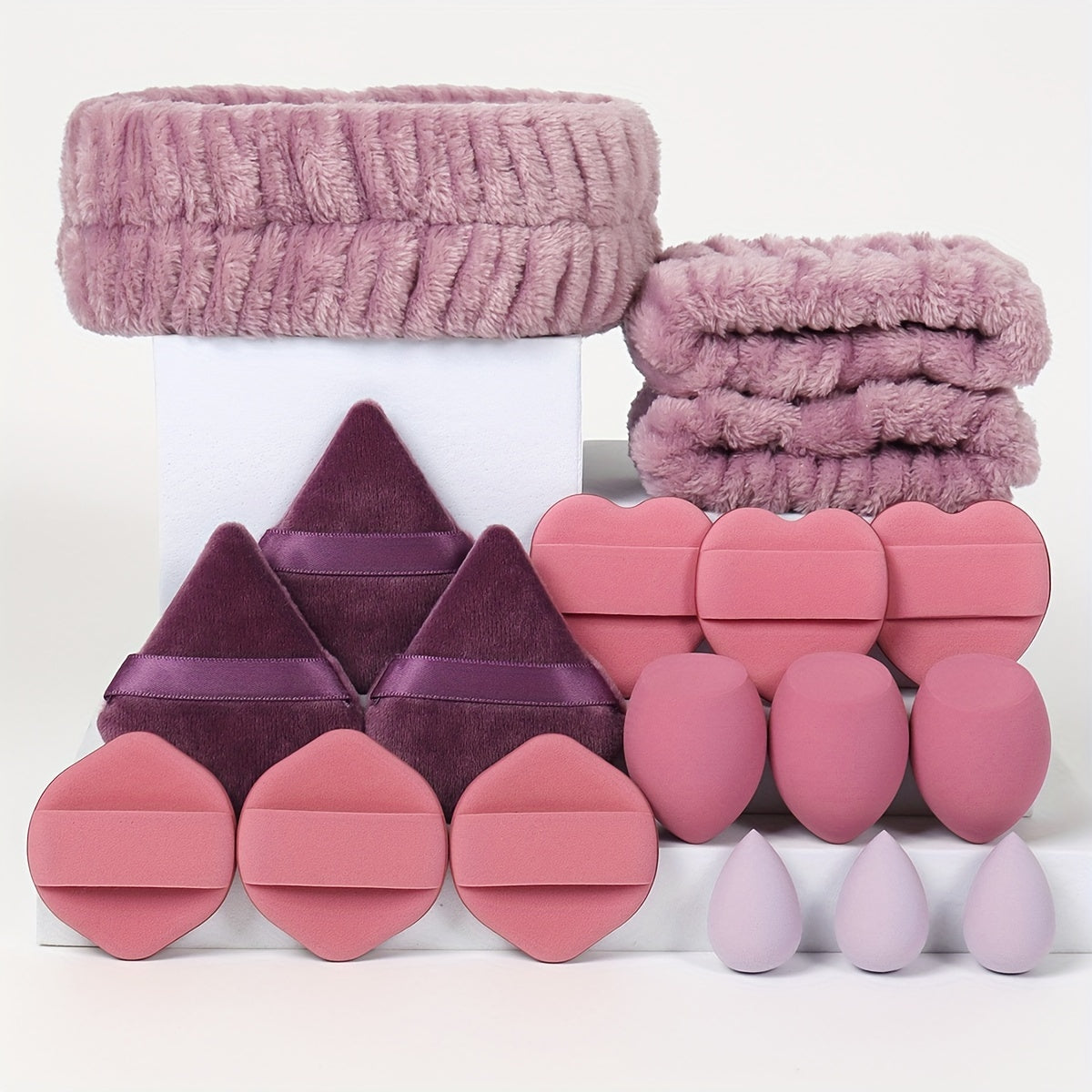 18-piece set including 1 hairband, 2 wristbands, 3 makeup sponges, 3 mini makeup sponges, 3 loose powder puffs, and 6 air cushion puffs. Features foundation mixing sponge for flawless