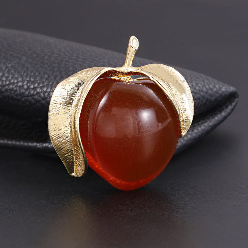 Vintage-inspired enamel brooch in a sophisticated peach design, featuring a high-end transparent finish. This fashionable fruit-shaped pin is a stylish accessory for clothing and suits.