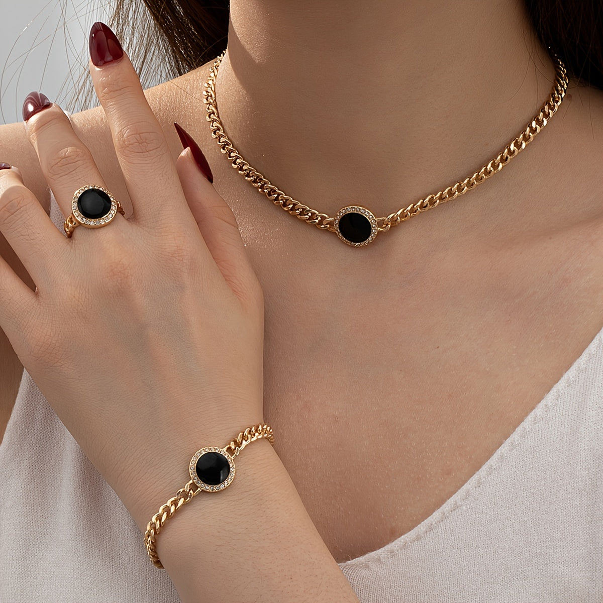 A collection of sleek and stylish black circular jewelry, including a necklace, ring, bracelet, and matching three-piece set.