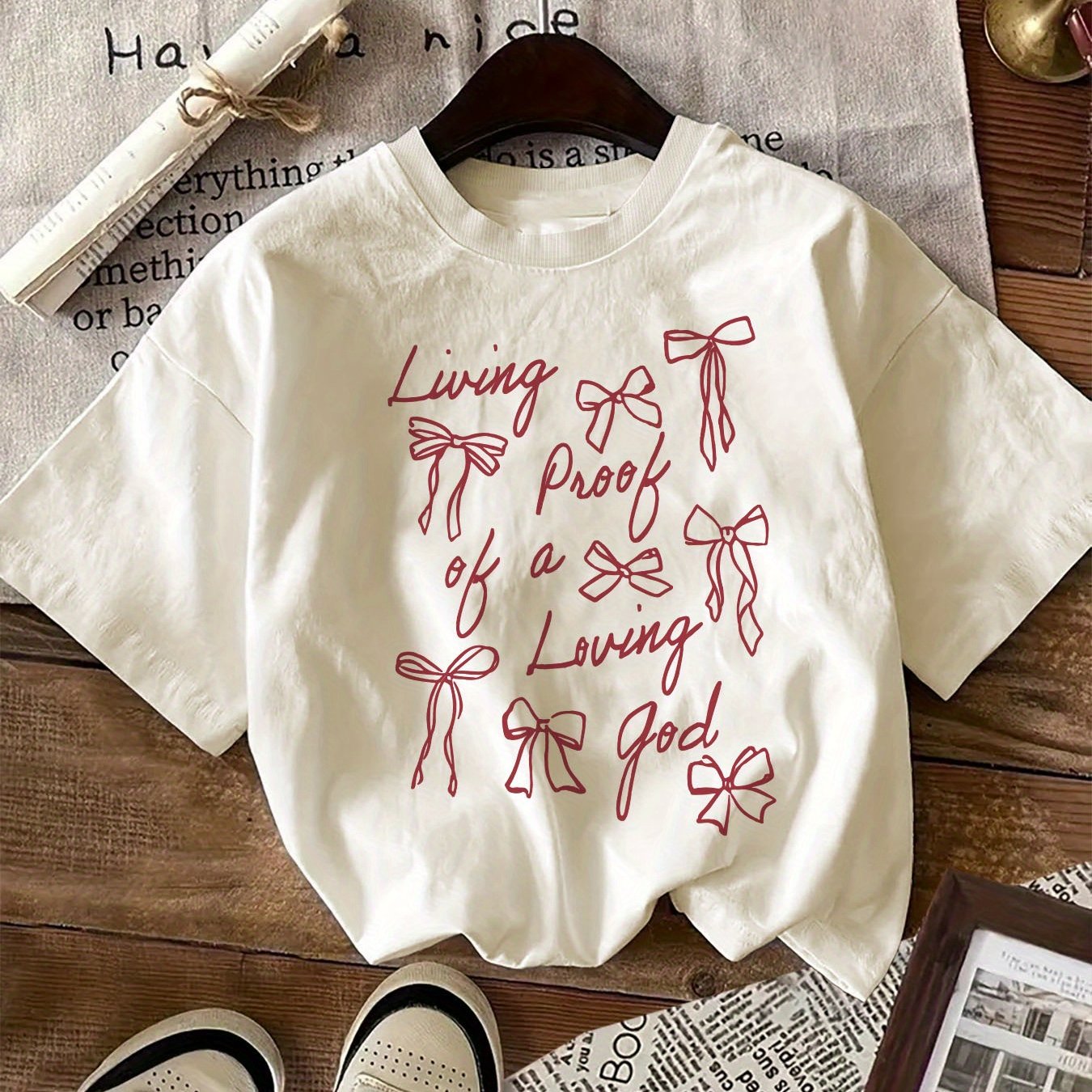 Unisex cotton crew neck t-shirt with 'Living Proof of a Loving God' alphabet and bow print design, suitable for all seasons.