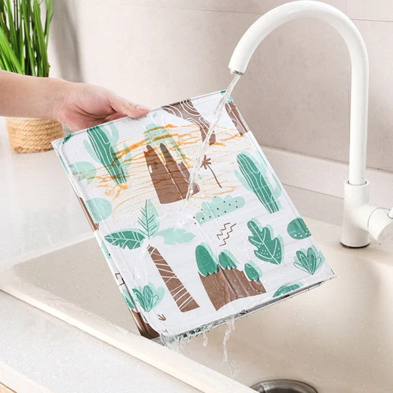 Kitchen stove baffle made of foldable aluminum foil featuring a tropical leaf pattern. This splash guard and cooking safety screen is perfect for deep frying and adding a touch of style to your kitchen decor. Use it as stove top protectors for added