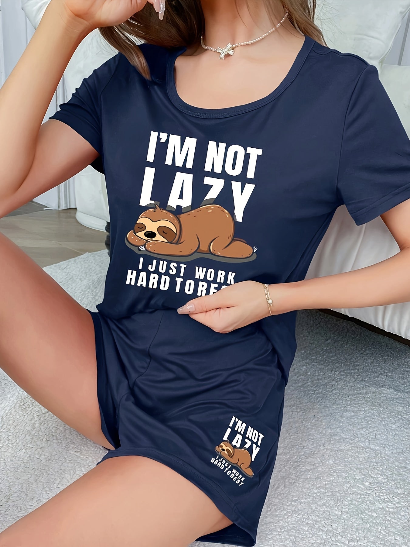 Women's sleepwear set with cute sloth print and slogan, including short sleeve top and elastic shorts.