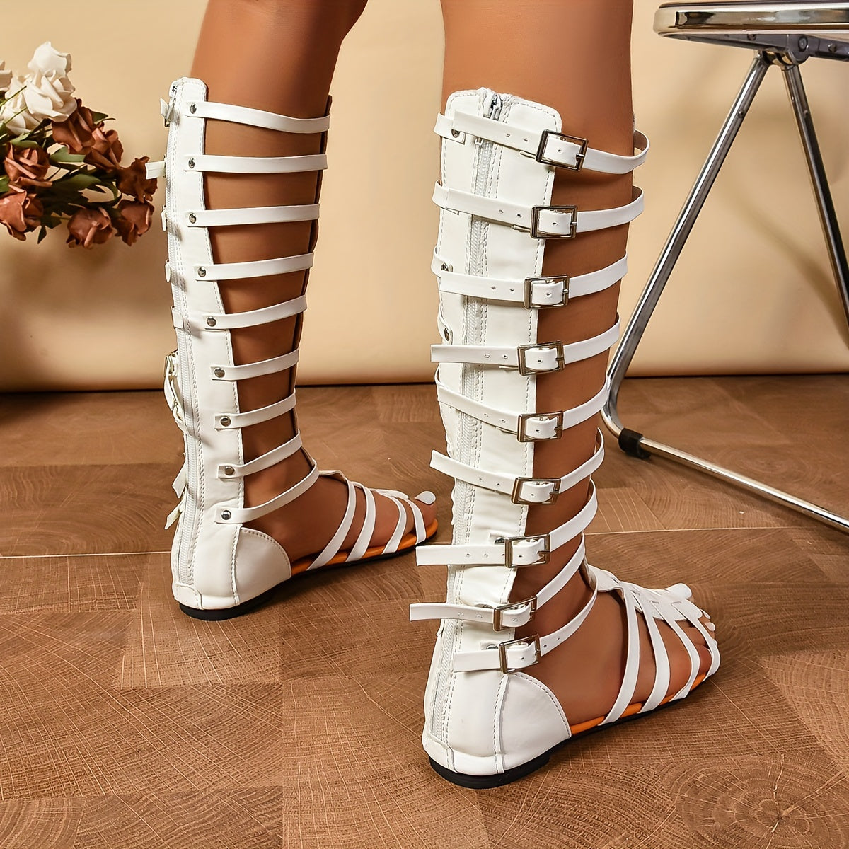 Fashionable flat sandals for women with metallic strappy knee-high design and buckle closure.