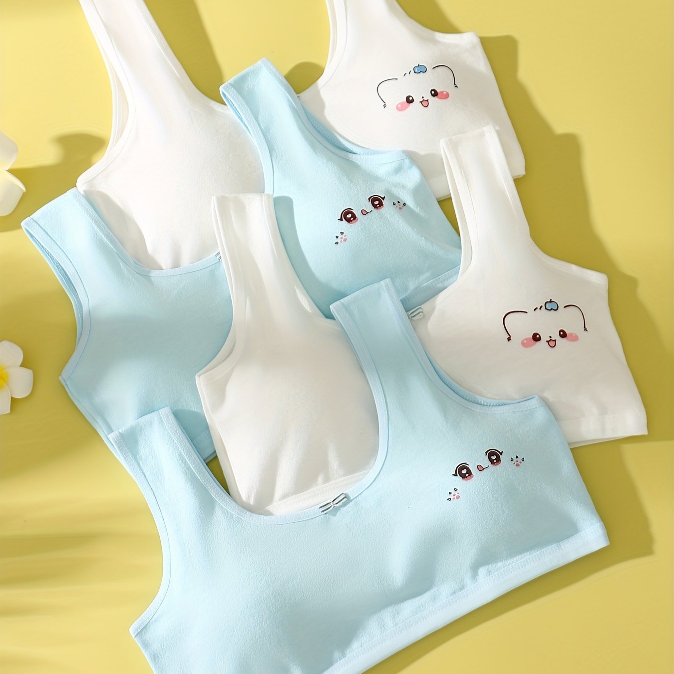 4 comfy cotton bras for girls aged 7-13 with cute animal illustrations in solid colors. Stretchy and machine washable. Includes white, yellow, blue, pink. Ideal for elementary to high