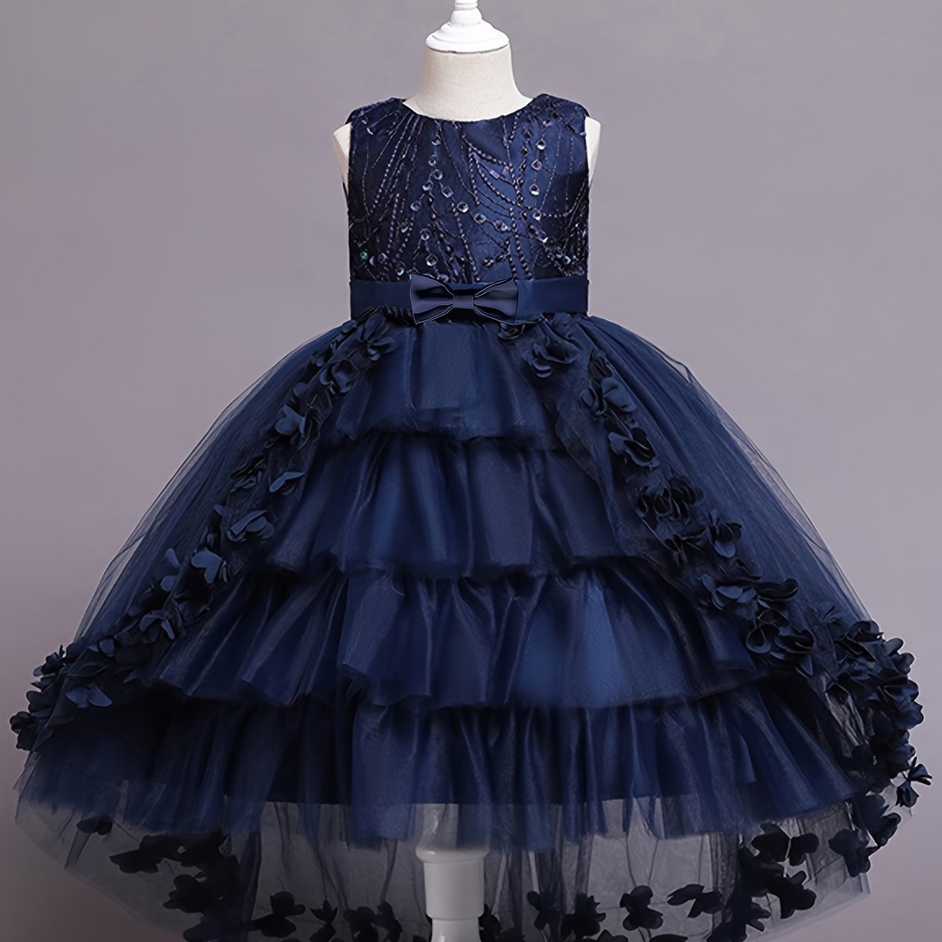 Elegant sleeveless princess dress with flowing tail, lace, and floral embellishments. Perfect for pageants, weddings, piano performances, and birthday parties. Made with tweedlike texture