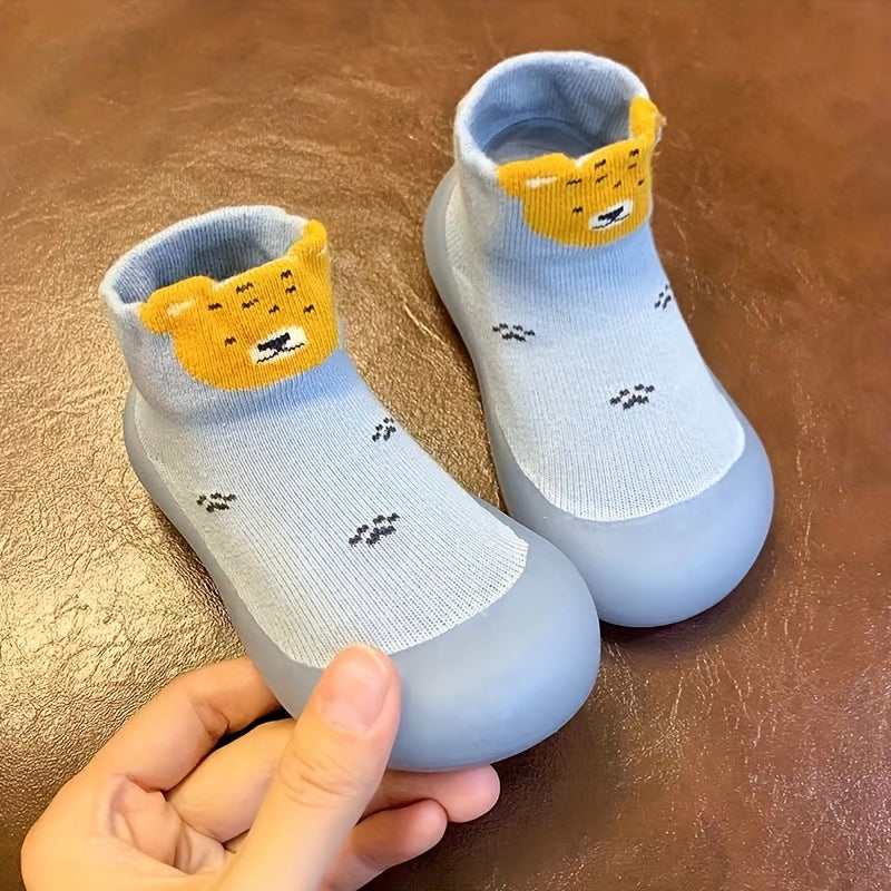 Cute lion cartoon slip-on sock shoes for baby boys in light blue with yellow accents. Soft, breathable, and non-slip rubber sole, perfect for first walkers in spring and fall.