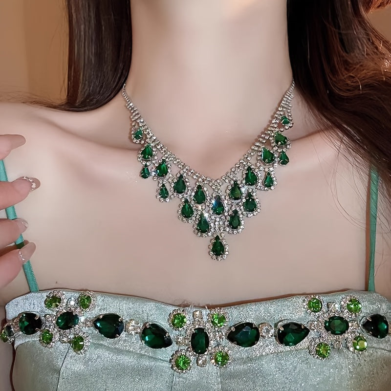 Elegantly designed in a vintage teardrop tassel style, this set features a luxurious green rhinestone necklace and matching earrings. Crafted with a copper base and plated in 18K gold, the earrings have 925 silver ear posts for a touch of sophistication.