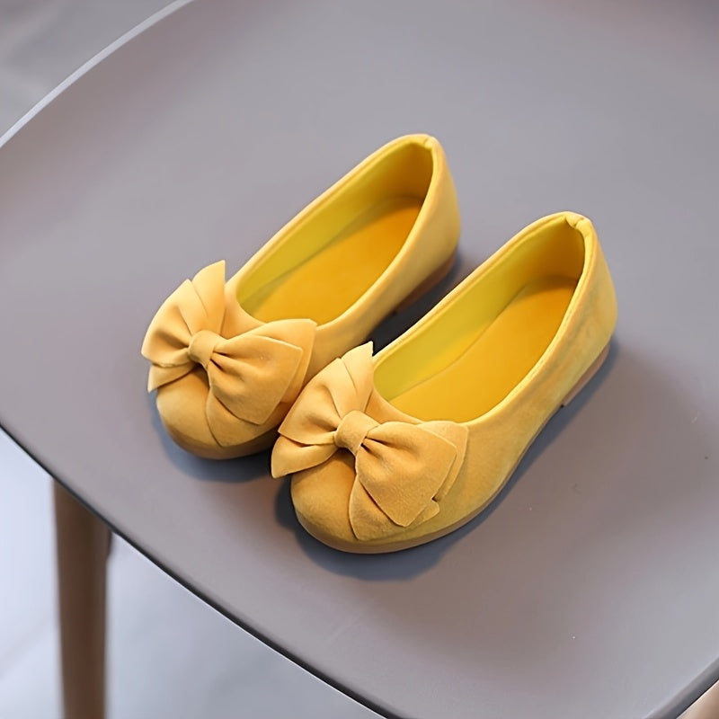 Stylish slip-on princess shoes for chic girls in pink, yellow, and black, with a bow detail. Made of comfy PU fabric with a rubber sole. Easy slip-on design for casual attire and