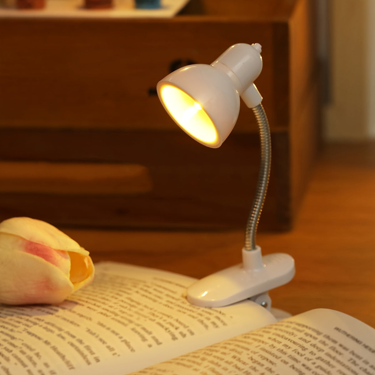 Mini portable LED book light with adjustable arm, warm light for night reading.