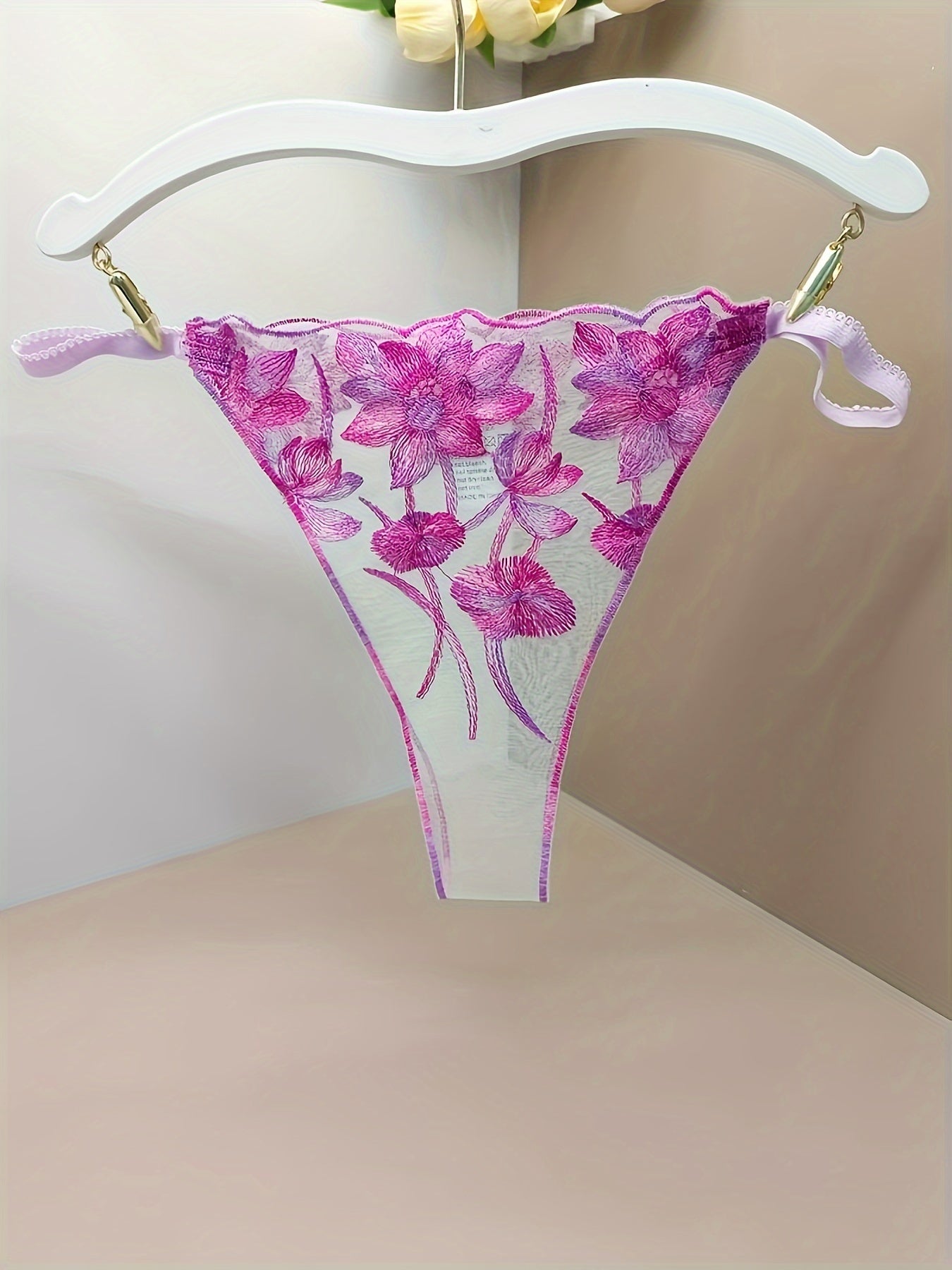 Women's sheer mesh thong panties with embroidered floral design and open crotch, featuring bow detail. Soft and breathable lingerie.