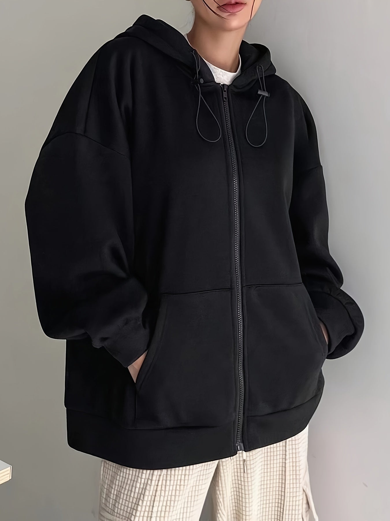 Black zip-up hoodie with fleece lining, long sleeves, loose fit, perfect for fall/winter, machine washable, features oversized hood.