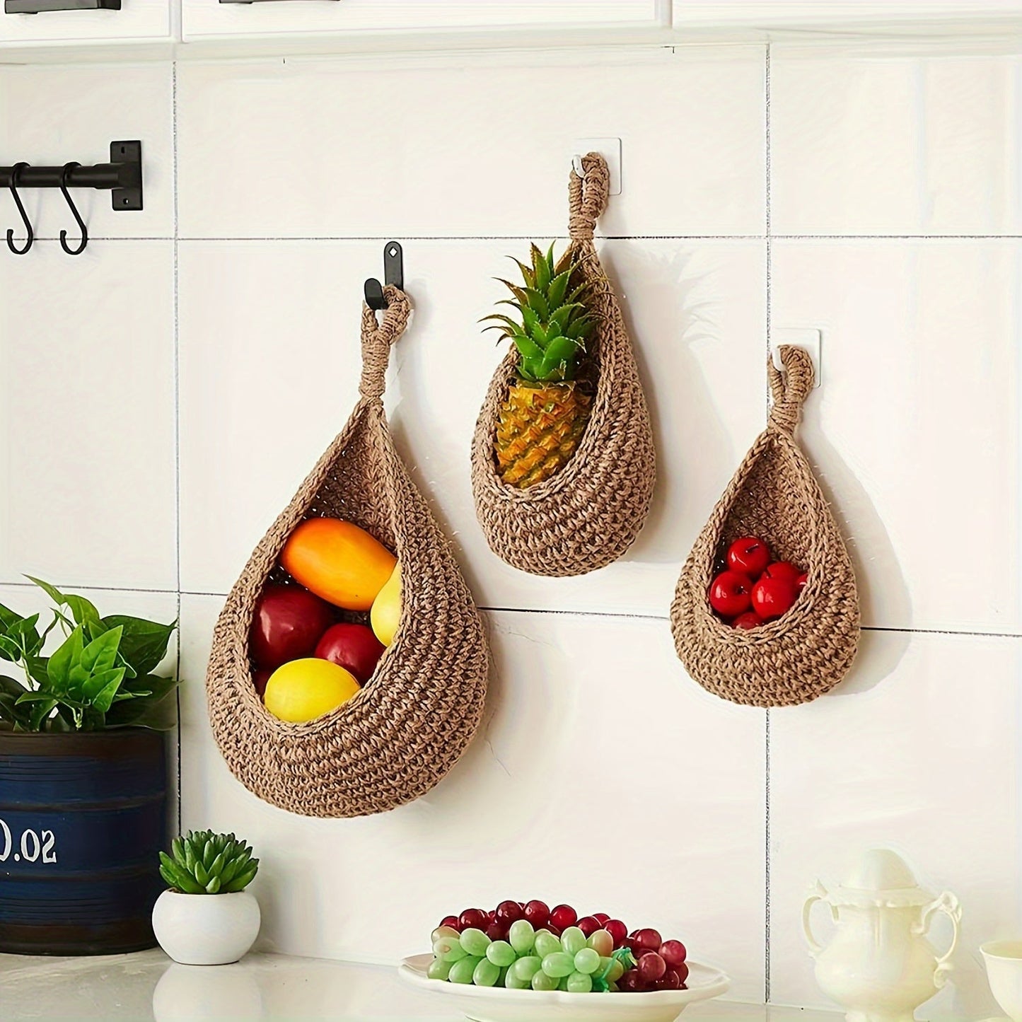 Set of 3 hanging baskets made of cotton rope and sisal crochet, featuring water drops design. This versatile storage solution can be used as a fruit, vegetable, or plant holder, or as a kitchen organizer. Hang them on the wall to save space and add a