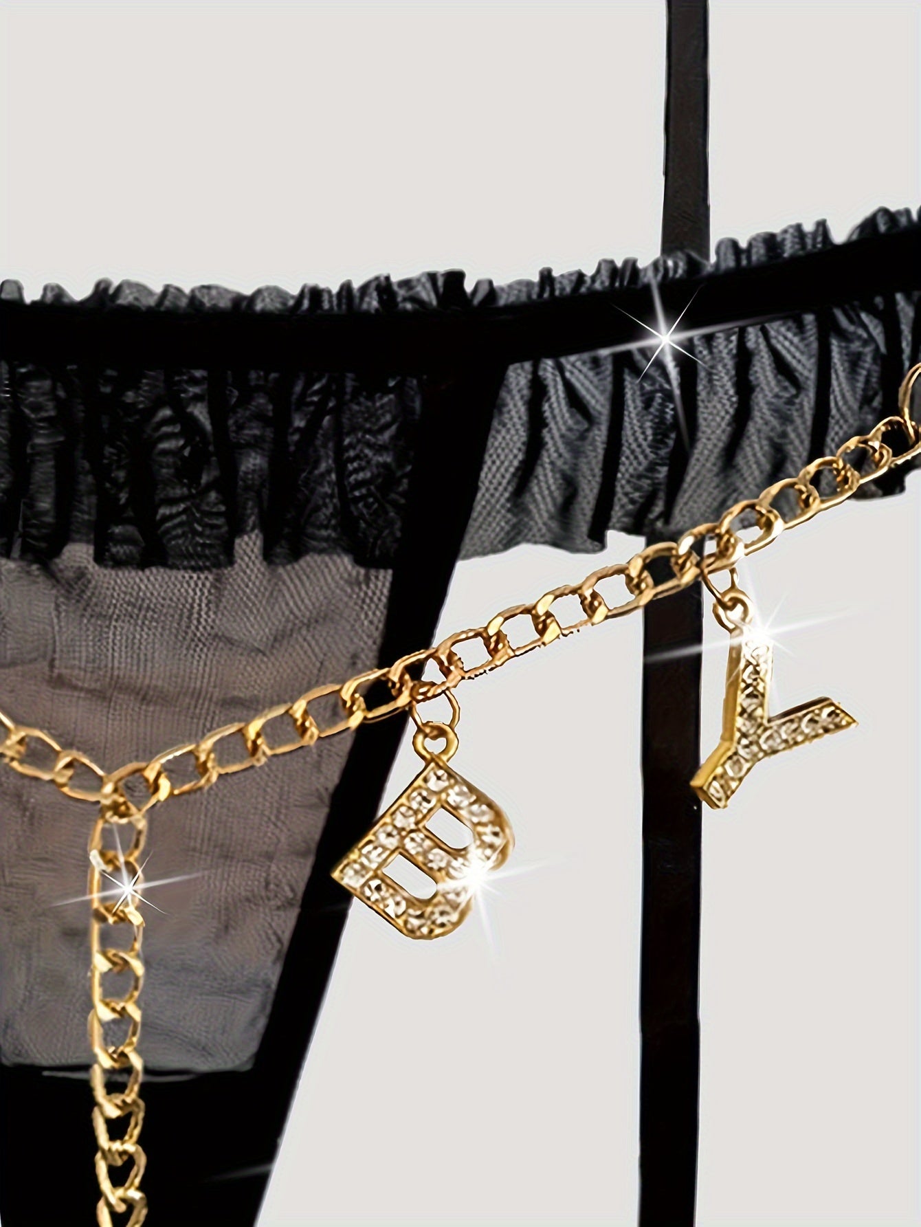 Seductive mesh garter set with gold chain, bow, and letter T-back.