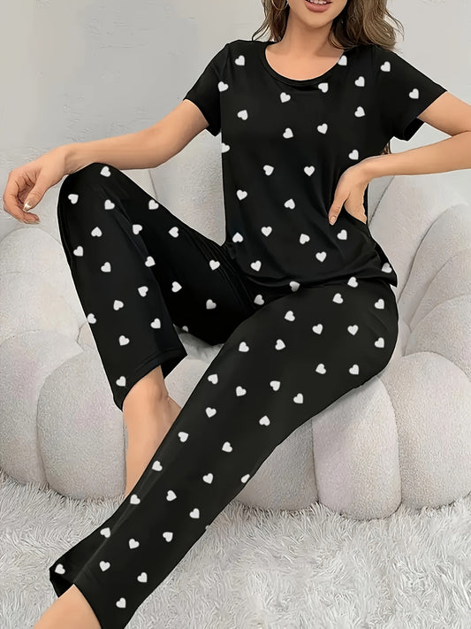 Black heart print pajama set for women includes short sleeve t-shirt and long pants. Made of cozy knit material that is machine washable. Blend of polyester and elastane.