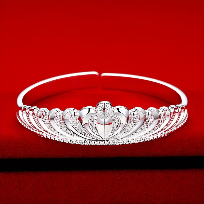 A stunning silver bracelet for women with a crown design, adorned with delicate flowers and shimmering stars. The bracelet features an elegant open mouth clasp for easy wearing.