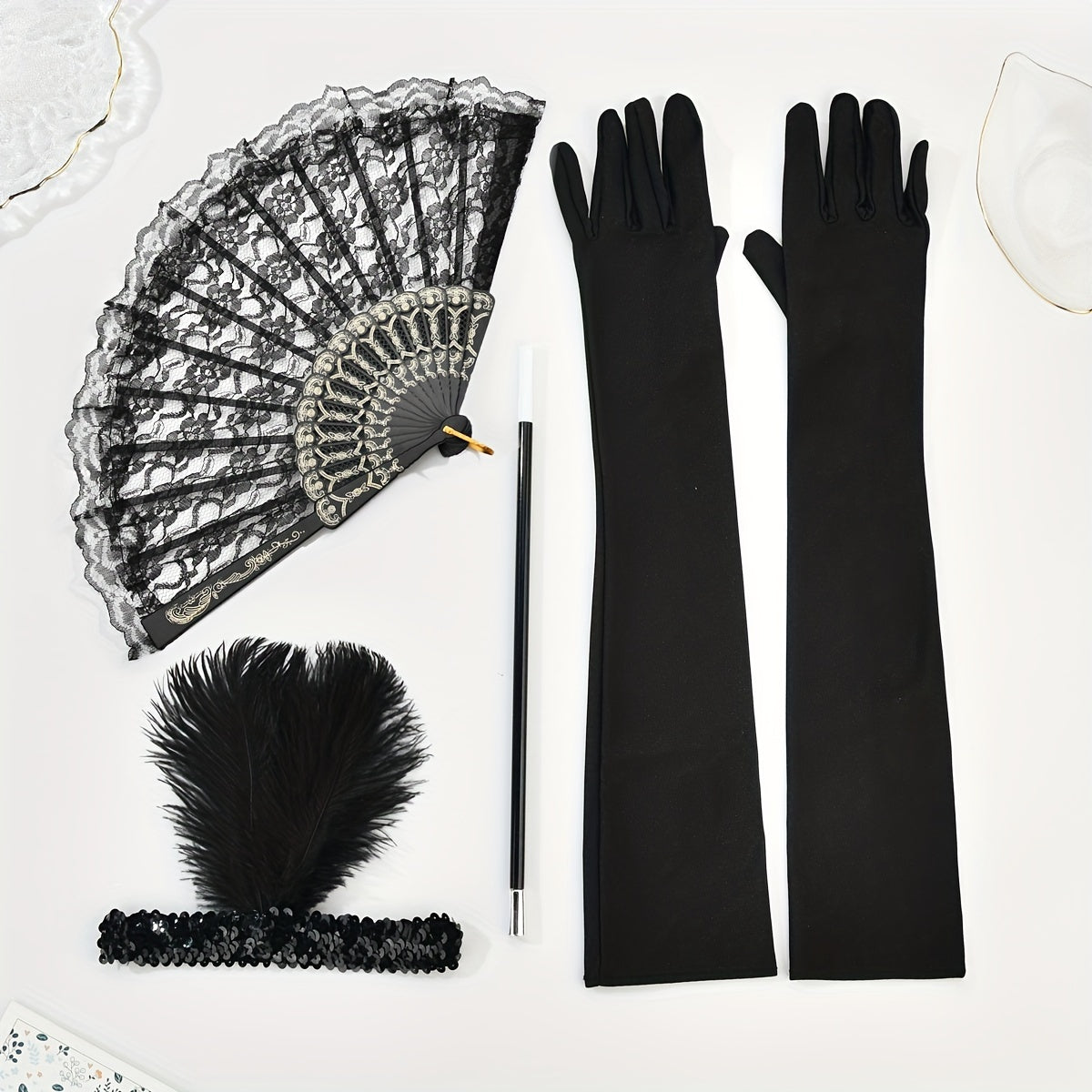 A collection of 1920s masquerade party accessories including gloves, faux feather hair clips, smoke tube fans, and other dress embellishments for women.