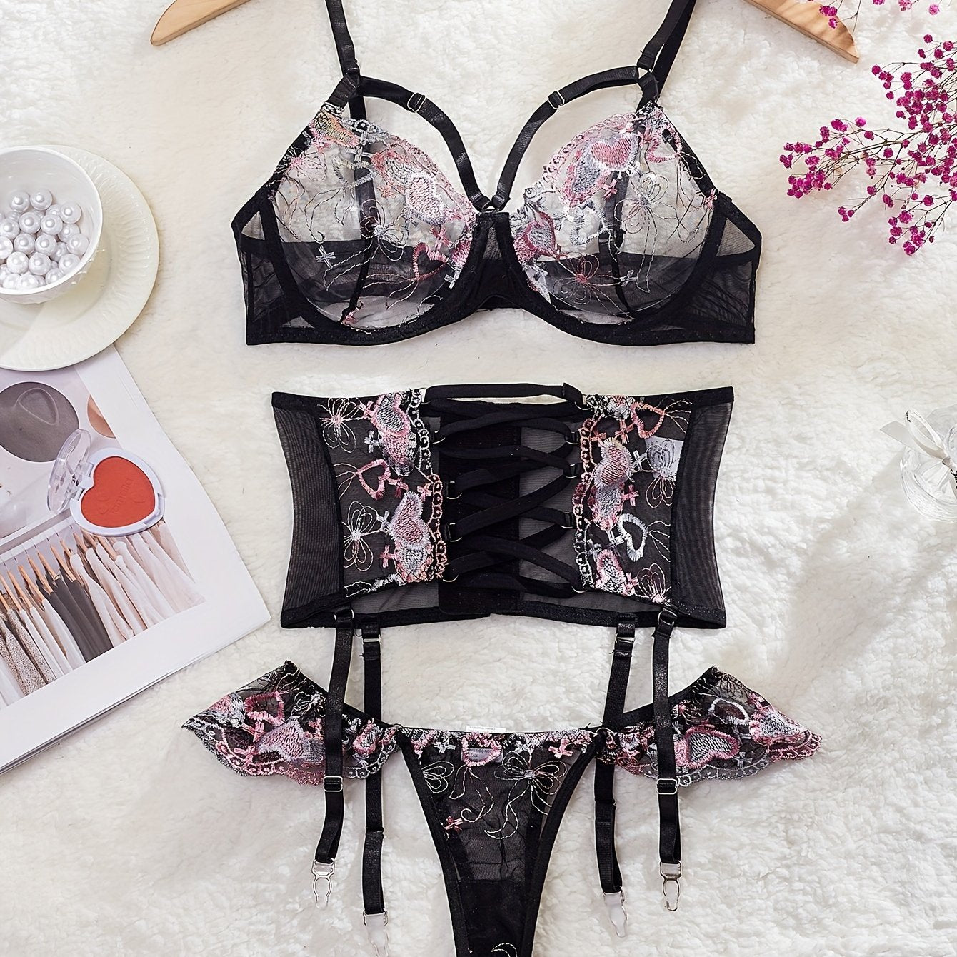 3-Piece lingerie set with heart embroidery, cross strappy detail, sheer mesh material in black with pink accents. Includes bra, garter belt, and thong.