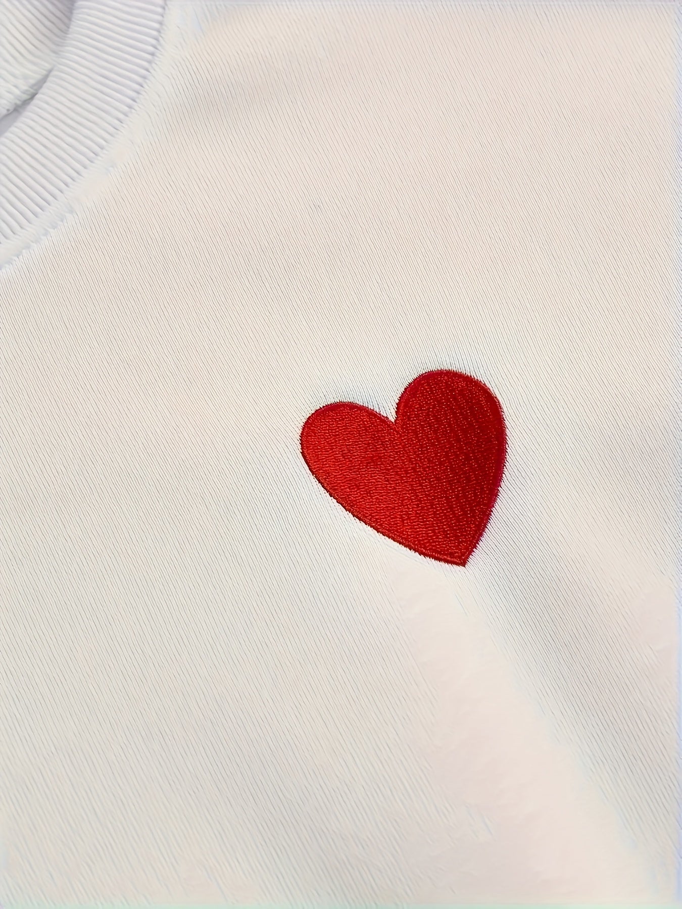 Women's embroidered heart pullover sweatshirt made of 100% polyester knit fabric with a crew neck and slight stretch. Ideal for all seasons as casual sportswear.