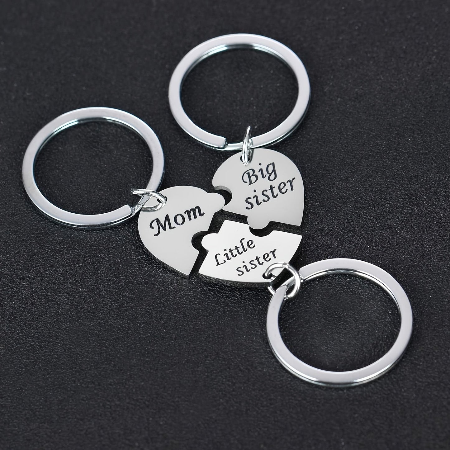 Set of three heart-shaped keychains for mothers and daughters, engraved with "Mom," "Big Sister," and "Little Sister." This matching pendant accessory set symbolizes family connection.