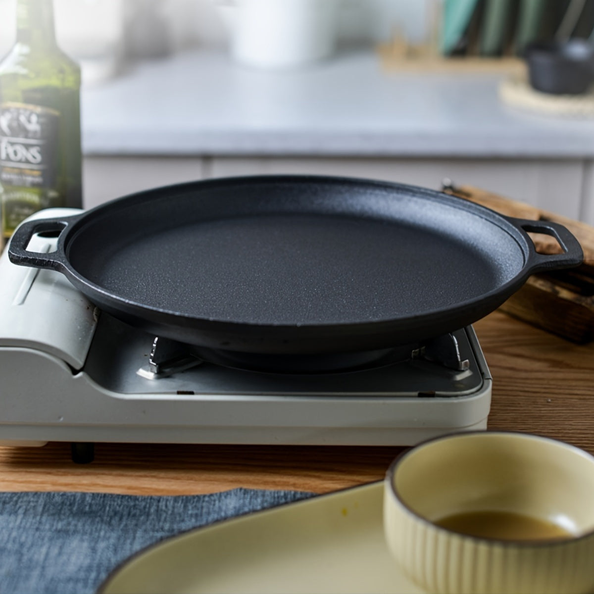 Double-handled non-stick frying pan for pancakes made of cast iron, meant for hand washing, with a durable uncoated surface ideal for cooking crepes and flatbreads.