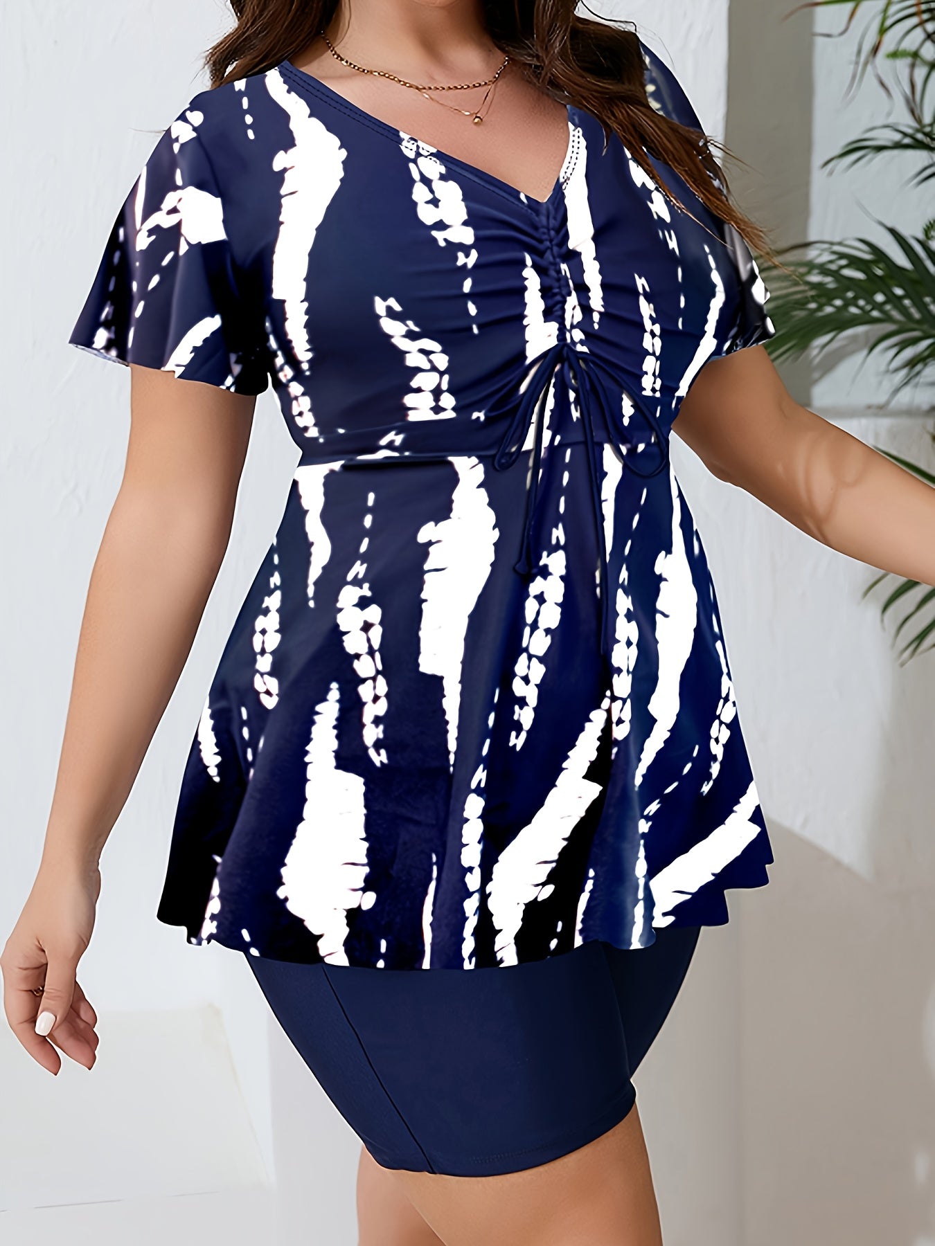 Navy Blue & White Abstract Print Tankini Set for Plus Size Women, V-Neck Top with Ruched Detail, Solid Black Shorts. Made of High-Stretch Polyester/Elastane Blend, Machine Washable.