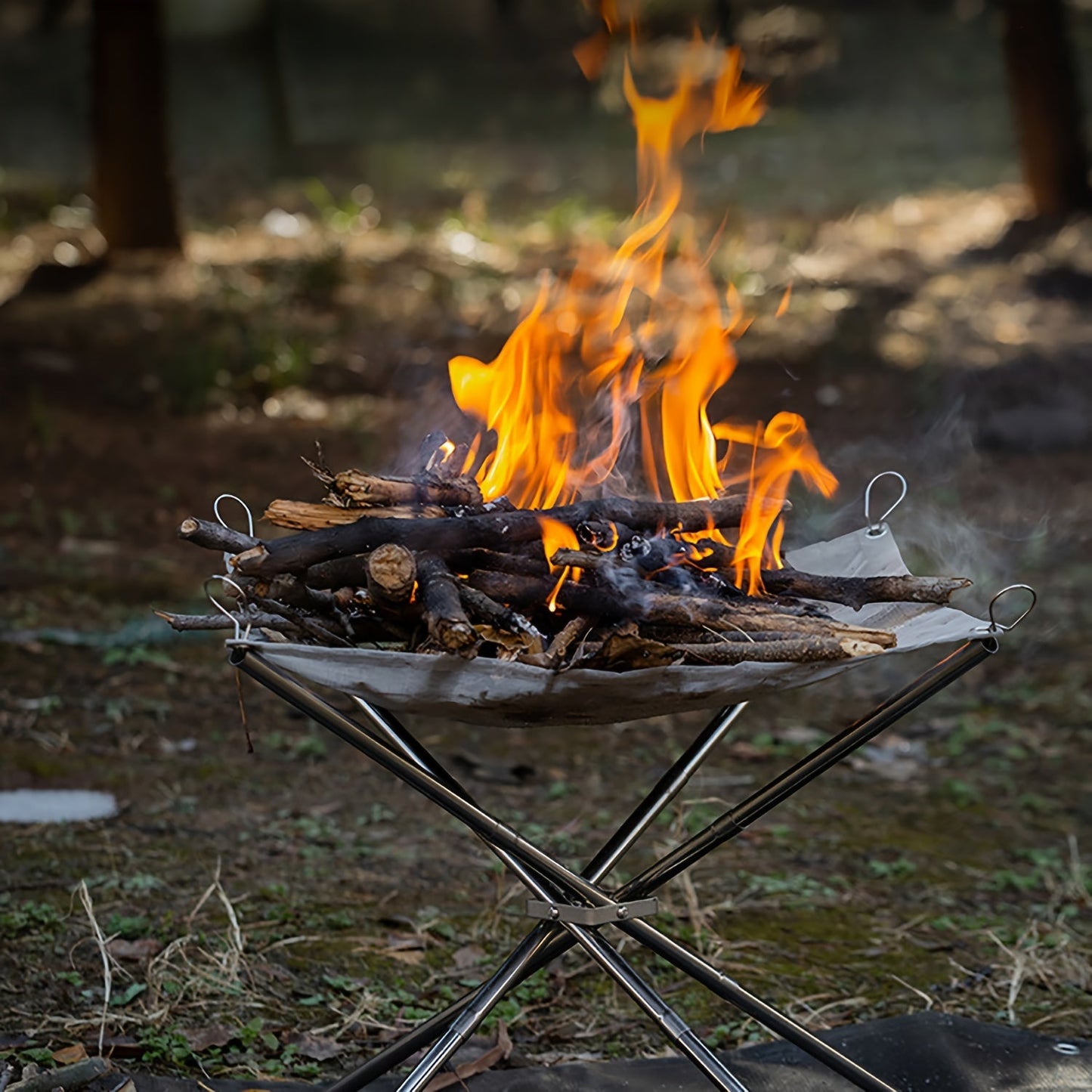 Portable Campfire Pit Grill made of stainless steel with a collapsible fire stand for camping, picnic BBQ. Includes a log carrier holder and carrying case.