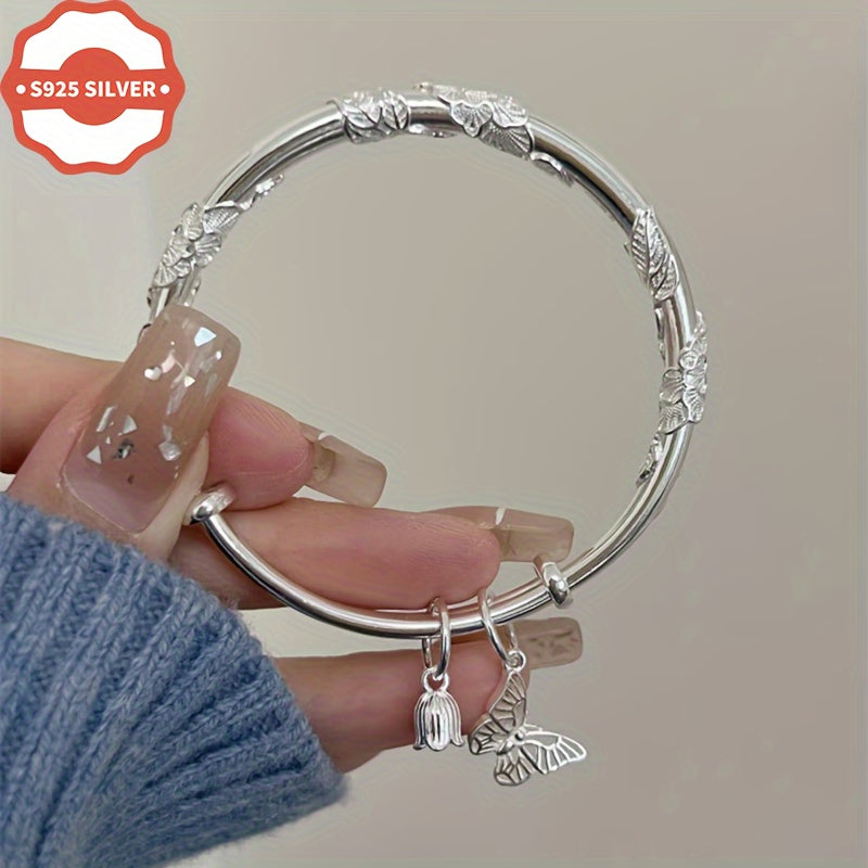 Add a touch of boho luxury to your wardrobe with this stunning 925 silver bangle bracelet featuring 18K golden plated charms. Handcrafted with floral designs, butterfly, and bell pendants, this hypoallergenic cuff is perfect for women who love unique