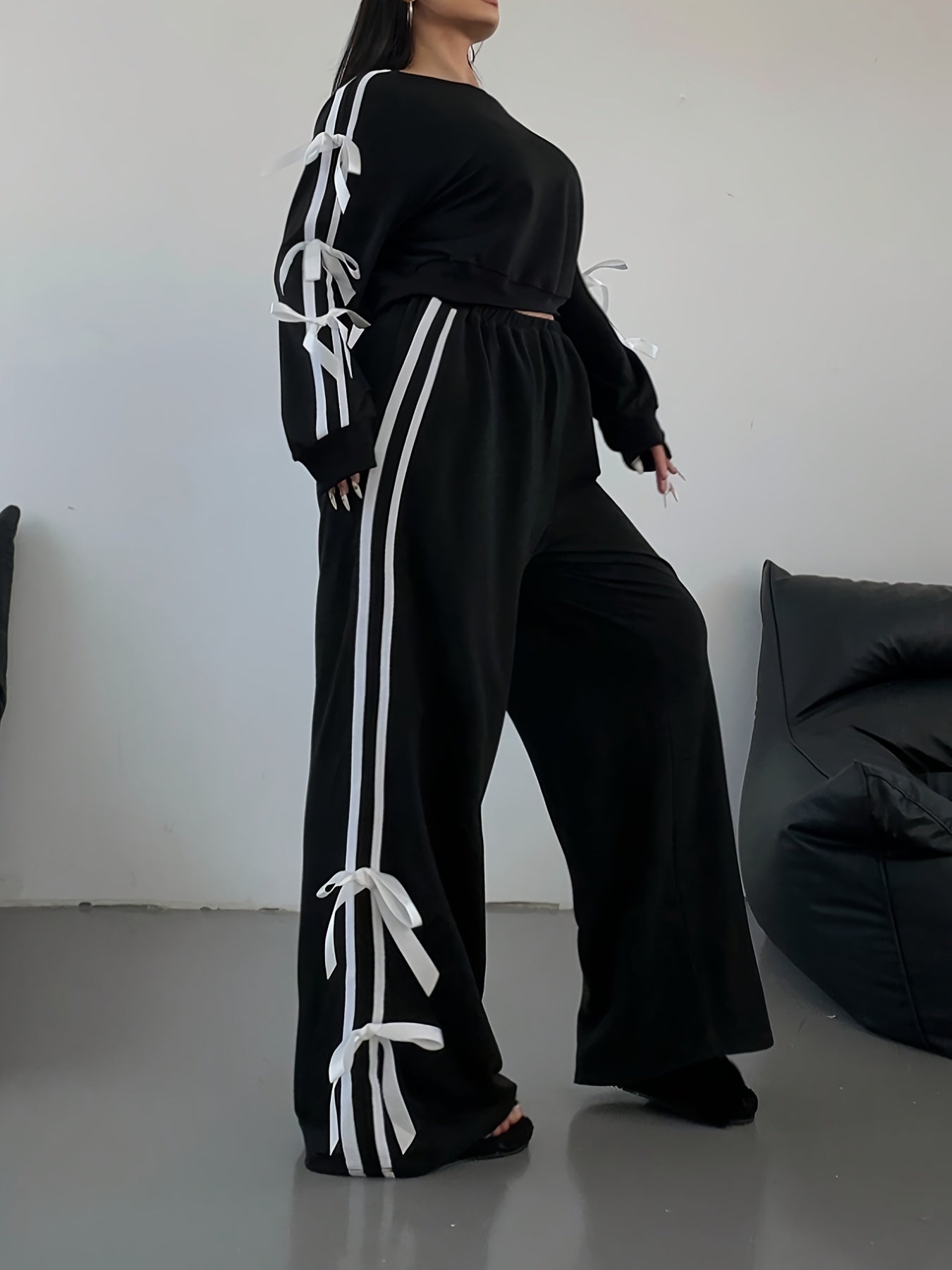 New two-piece set for plus size women with crop top, long sleeves, striped wide-leg pants, bow, and drawstring decorations.