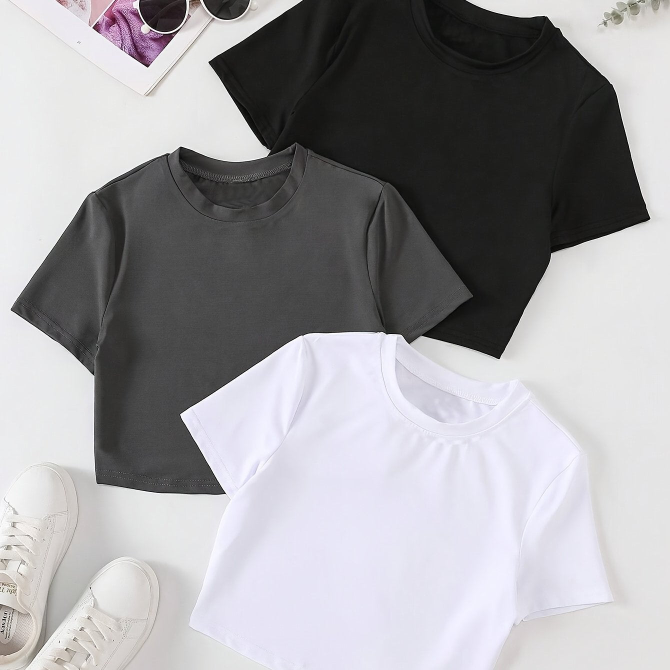 Three women's slim fit crop tops in black, white, and dark gray. Made of polyester and machine washable. Great for layering.