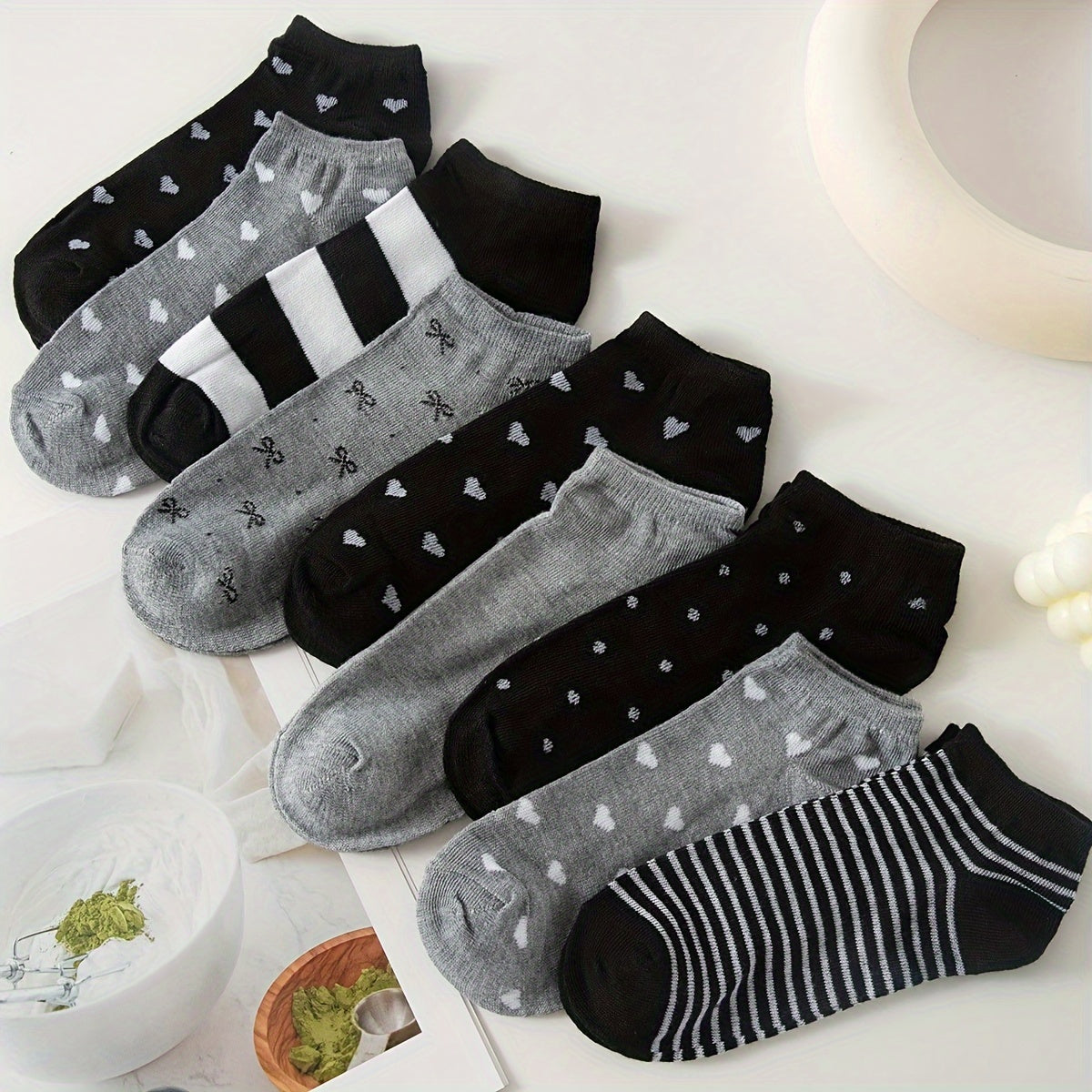 Women's ankle socks in black and grey with assorted geometric patterns. Made from comfortable knit fabric, 95% polyester and 5% spandex. Random style shipping. 10/20 pairs available.