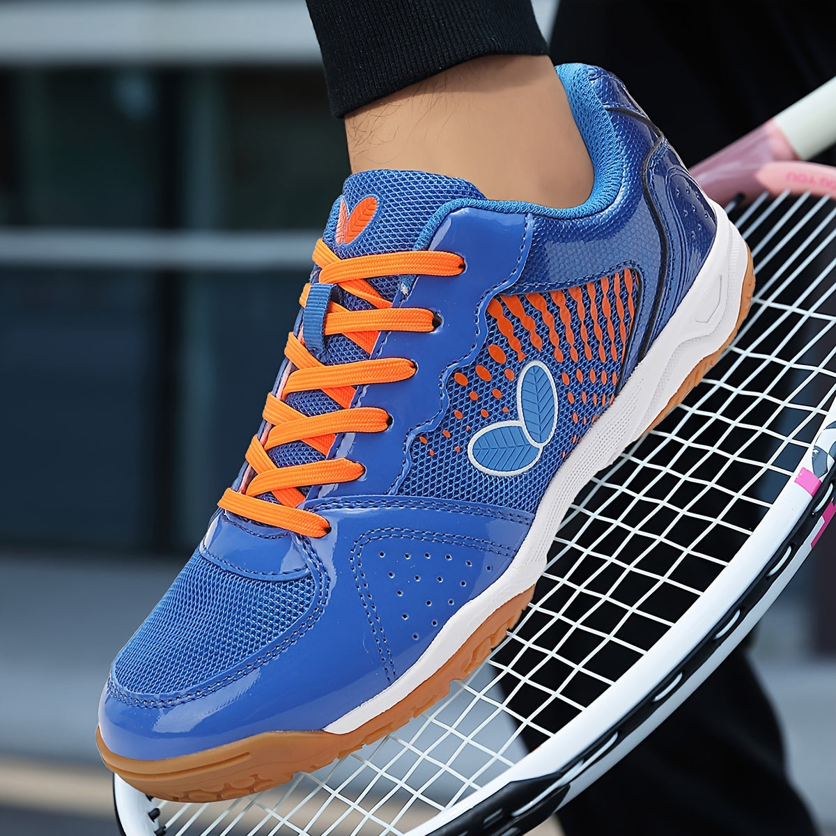 Breathable badminton and table tennis shoes in blue with orange accents, featuring a durable sole and lace-up design for all-season athletic wear.