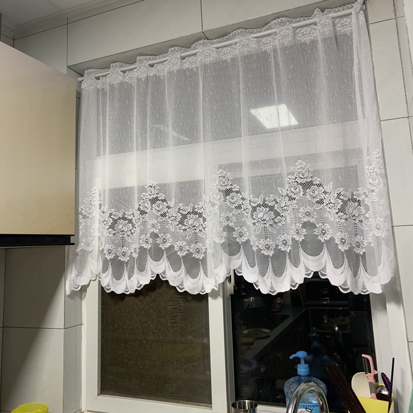 Bring elegance to your windows with our 1-piece White Lace Sheer Curtain featuring delicate floral patterns. This curtain has a rod pocket, scalloped bottom, and is made of lightweight polyester voile, perfect for dining rooms and kitchens. It is