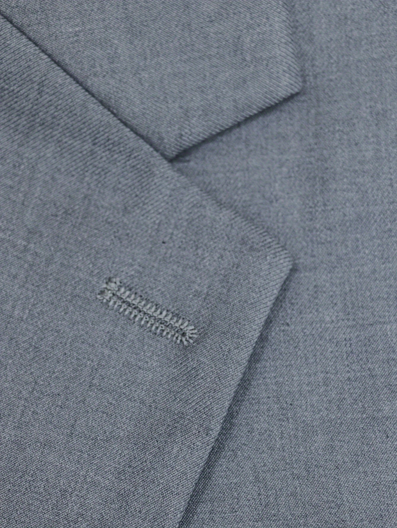 Men's gray two-piece business suit jacket with pockets still sewn shut.