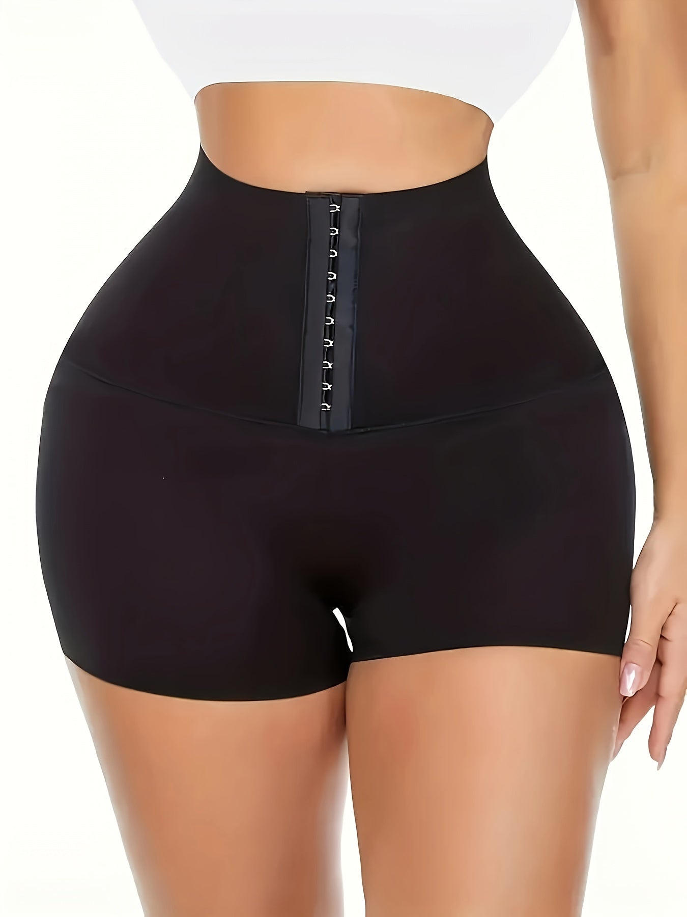 High-waisted tummy control yoga shorts for women in black, with front hook-and-eye closure for slimming waist trainer. Made of breathable polyester and elastane blend for mid-support knit