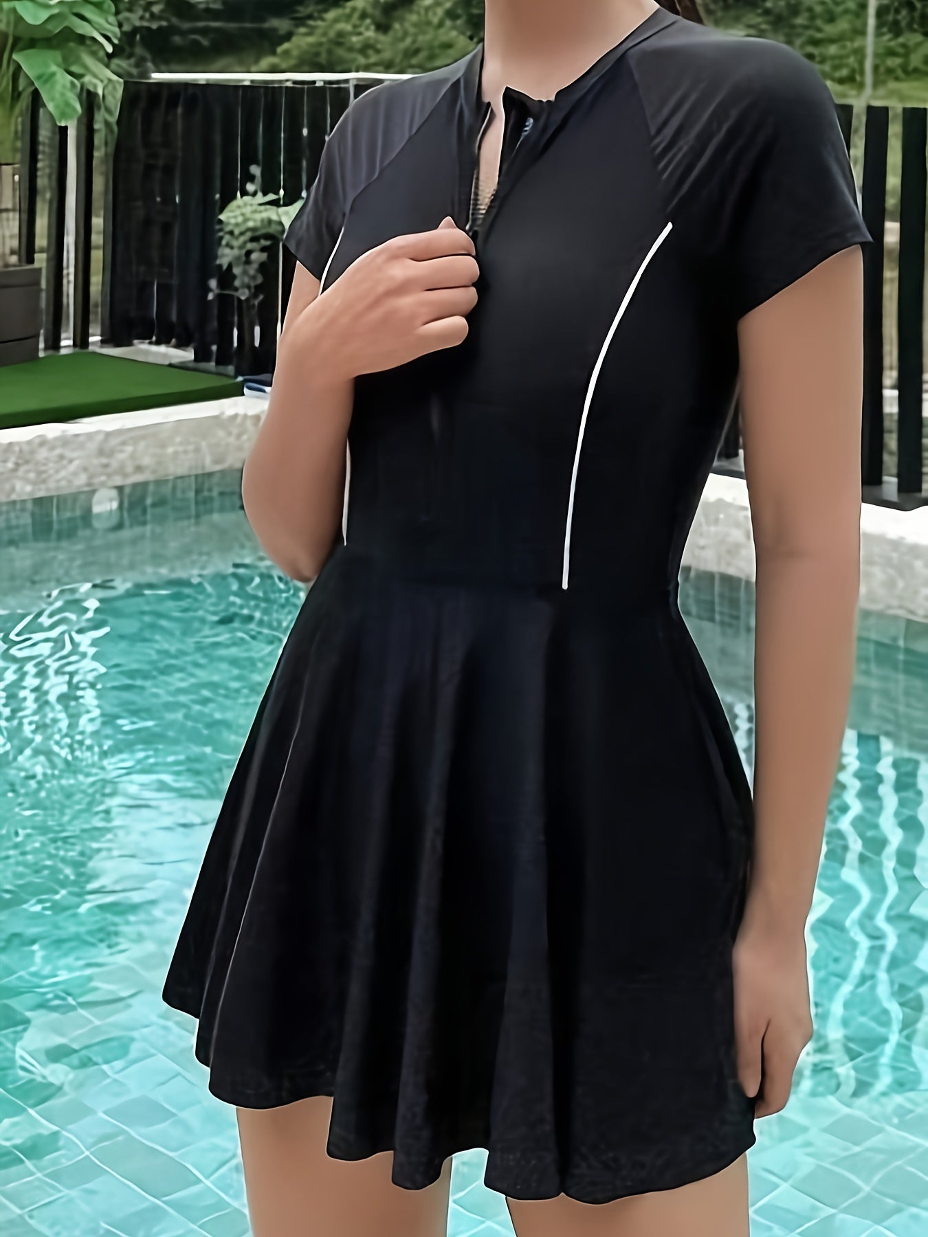 Sporty black one-piece swimsuit for women with zipper detail, made from high stretch nylon/elastane blend. Features short sleeves, round neck, and non-transparent fabric suitable for