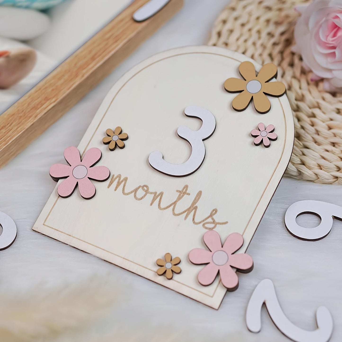 Wooden milestone cards set: track your baby's growth with monthly milestone discs featuring a floral AA design. Perfect for photo props and announcing your little one's first year. Includes discs for each month from 1 to 12.