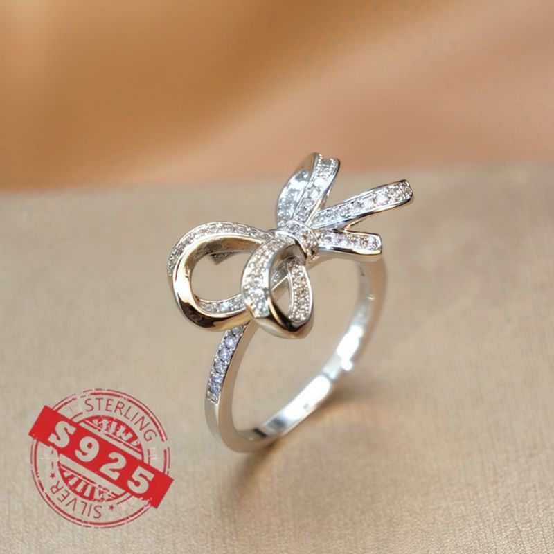 Chic 925 Sterling Silver Ribbon Bow Tie Ring featuring Natural Zirconia, perfect for July Birthdays. This Tribal & Cute style ring is 925 Silver Plated, Tarnish-Resistant, and adorned with Heart-Themed details. Ideal for Daily Wear or Wedding occasions