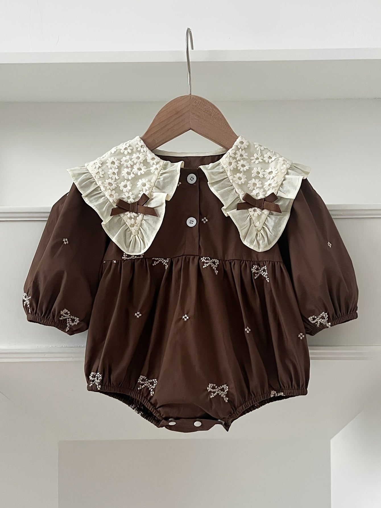 Stylish floral embroidered long-sleeve romper for baby girls, made of cotton with bow detail, ideal for spring/fall and outdoor wear.