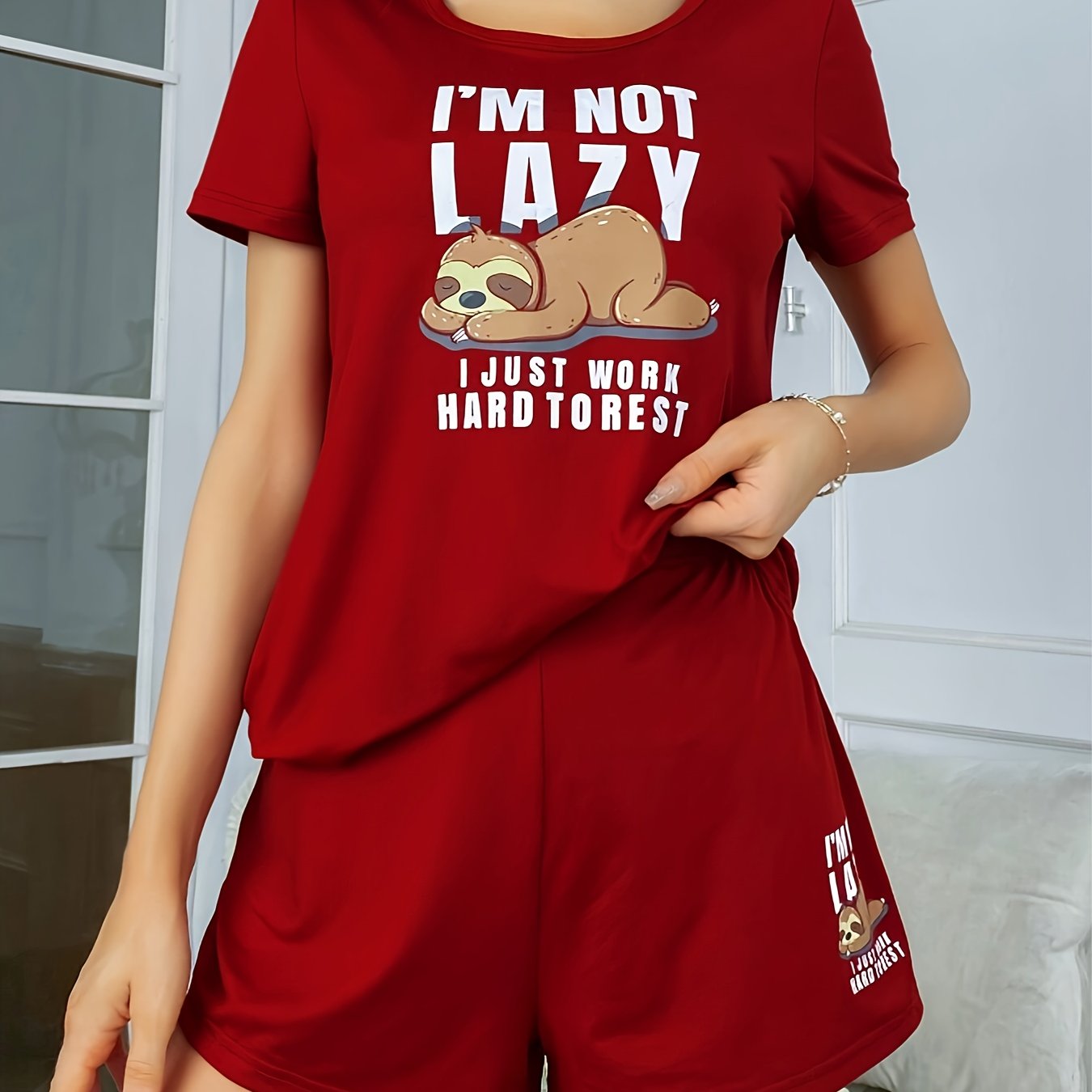 Women's sleepwear set with cute sloth print and slogan, including short sleeve top and elastic shorts.