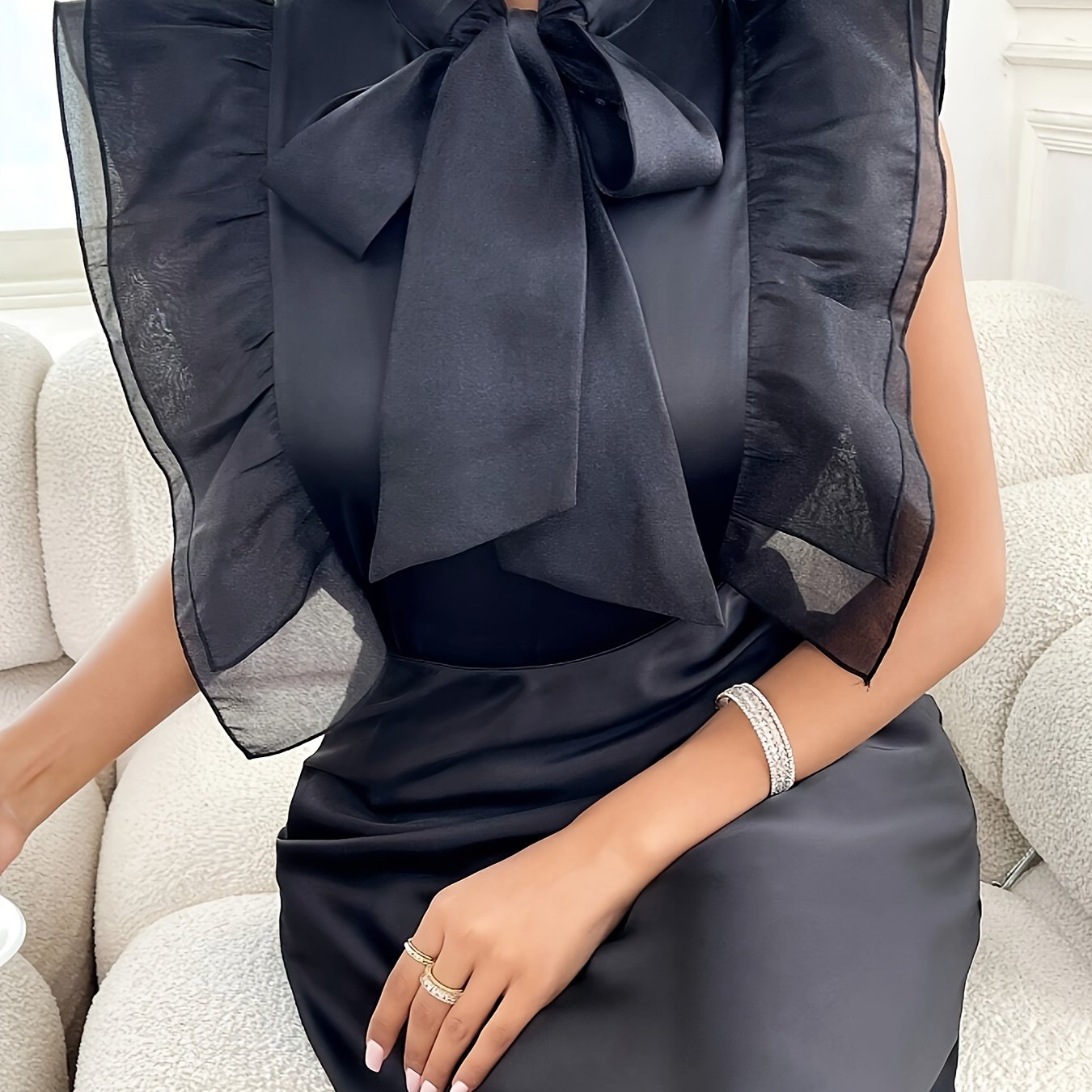 Chic solid black blouse with flutter sleeves and bow tie detail. Made from machine washable polyester, perfect for all seasons and occasions.