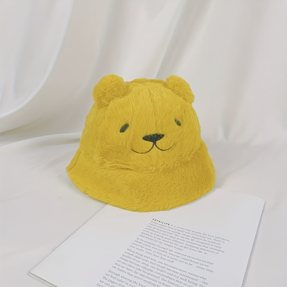 Women's fuzzy bucket hat with cute bear embroidery in yellow and white. Hand washable for cozy winter wear.