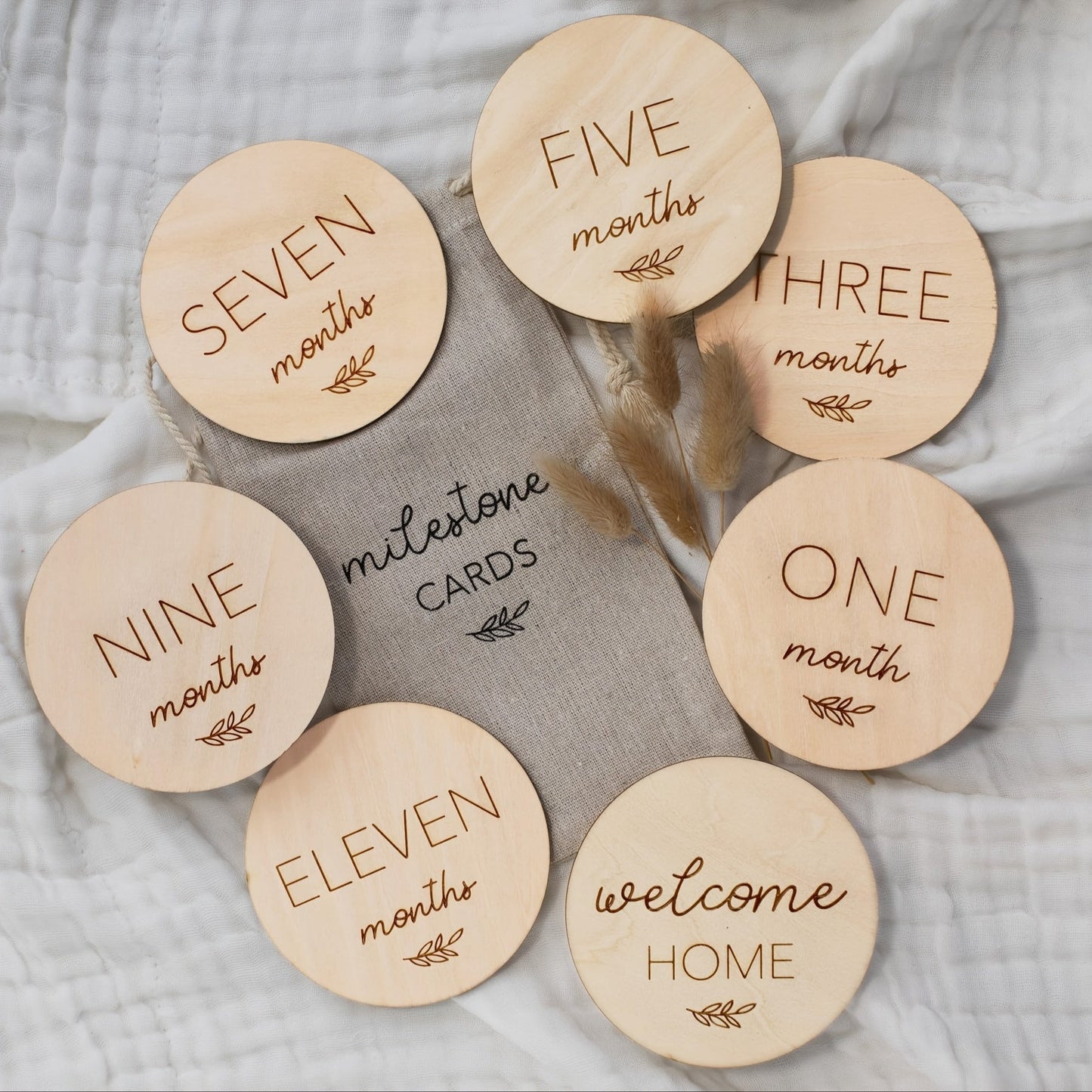 Celebrate baby's first year with the Yuebaaf 7-piece Reversible Wooden Milestone Cards Set! This set includes milestone cards featuring 'Hello World' and Announcement signs, perfect for monthly photo props. Made from durable fiberboard discs, these cards