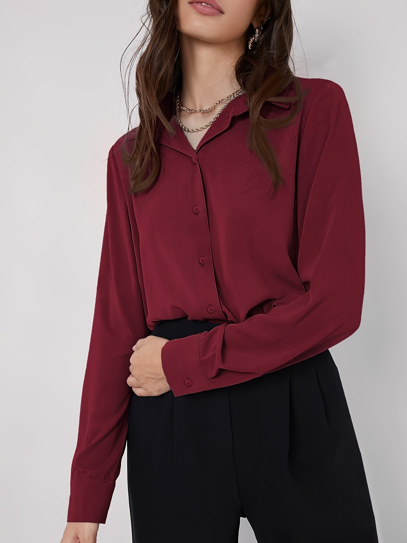 Stylish maroon button-up blouse for women, with long sleeves, curved hem, and made of machine-washable polyester blend. Perfect for work or casual wear.