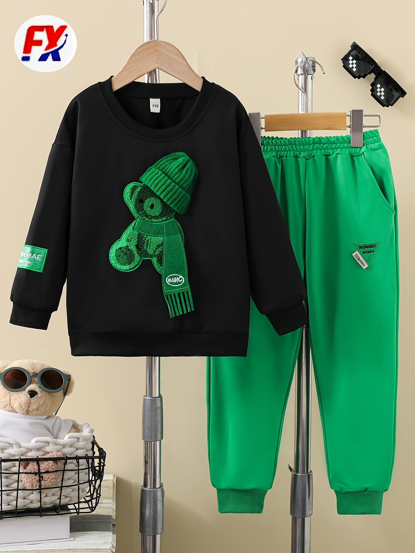 Boys' two-piece suit for outdoor wear with bear print hat, black sweatshirt, and green letter logo trousers.