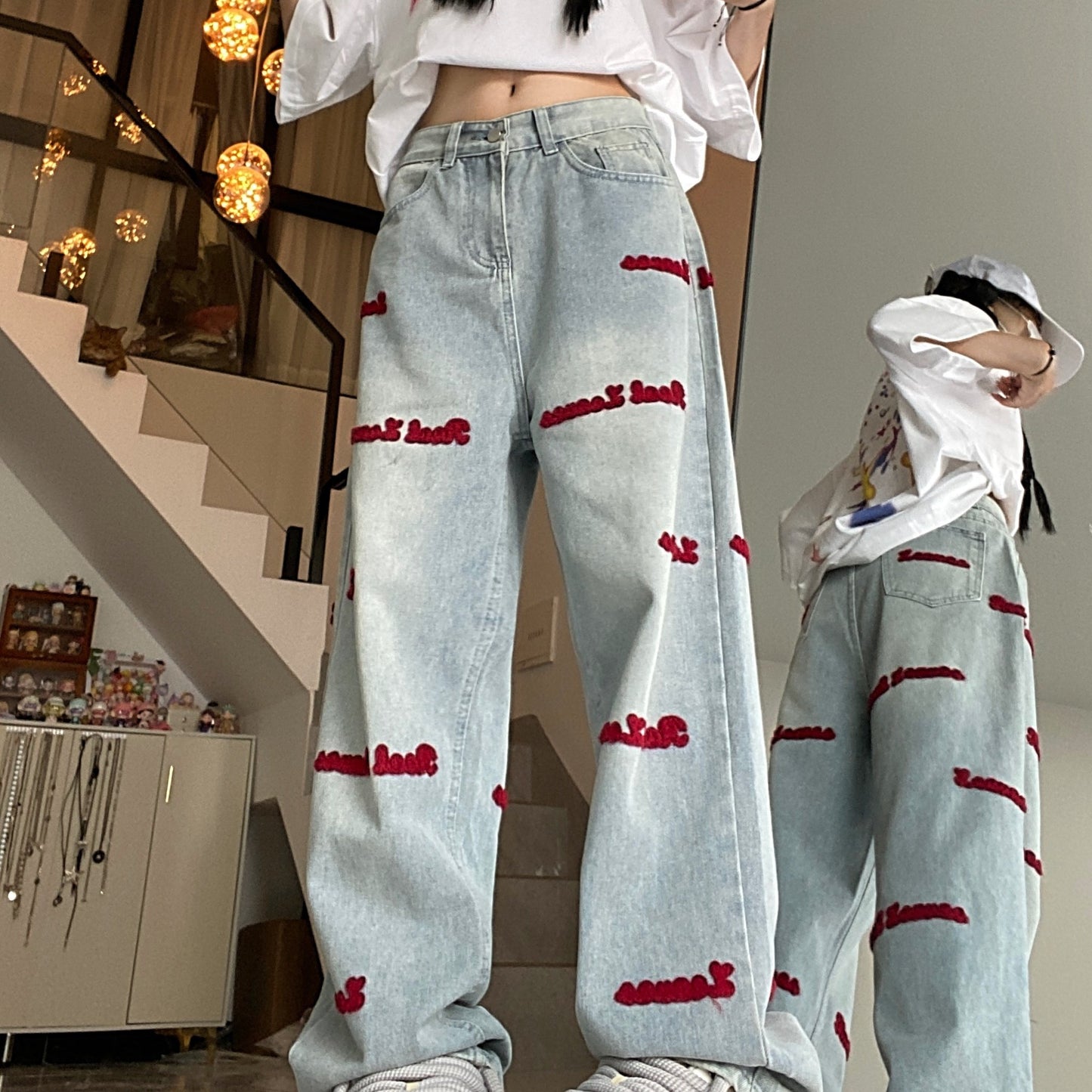 Women's denim jeans with red embroidered lettering, stretch fabric, regular fit, button closure, and washed denim detail. Casual style suitable for all seasons.