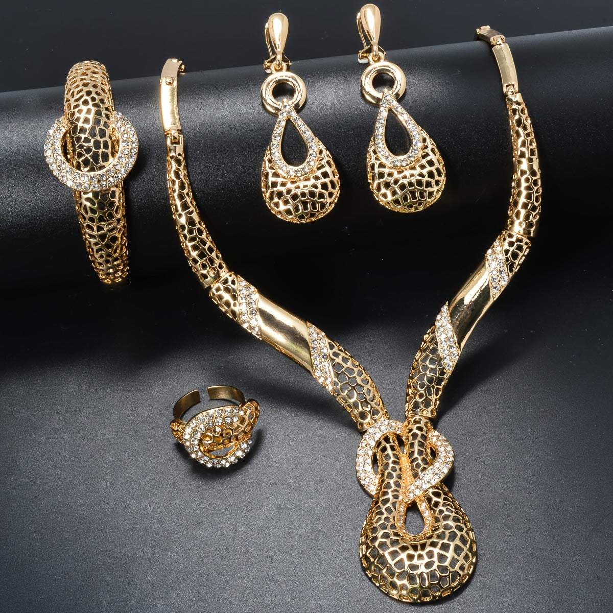 ZEADEAR presents a sophisticated gold-tone jewelry set featuring geometric cutouts. This luxurious collection includes a stunning Y-shaped necklace, bracelet, earrings, and ring, ideal for weddings and parties.