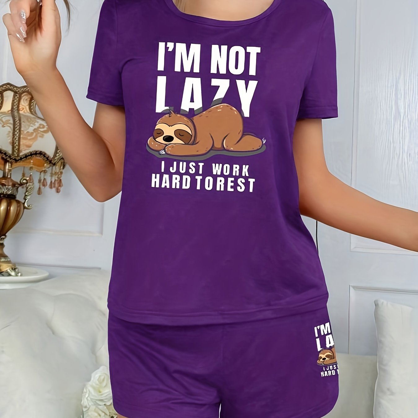 Women's sleepwear set with cute sloth print and slogan, including short sleeve top and elastic shorts.