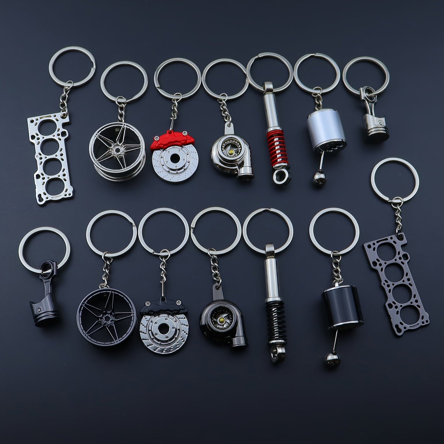 Funky car modification keychains set includes seven pieces: piston, turbo, wheel hub, gear shift, shock absorber, brake disc, and engine block. Made of zinc alloy in a sleek black finish.