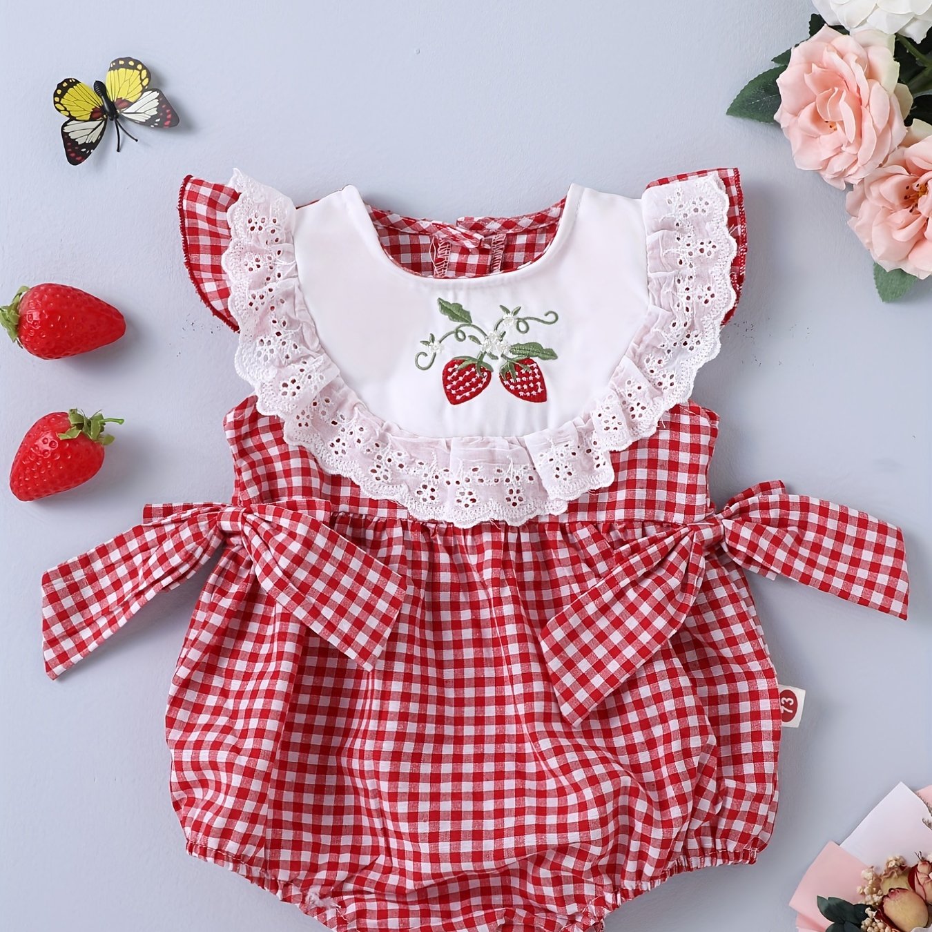 Infant girls' plaid onesie with strawberry embroidery and bow details, suitable for casual outdoor wear.